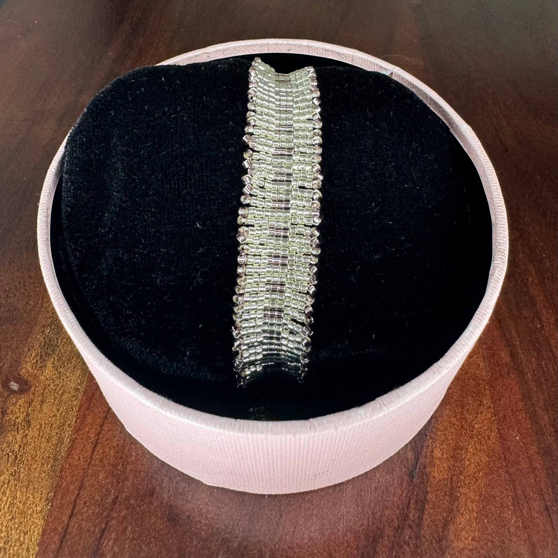 Silver bracelet in a white box on a wooden surface