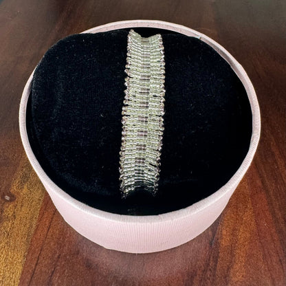 Silver bracelet in a white box on a wooden surface