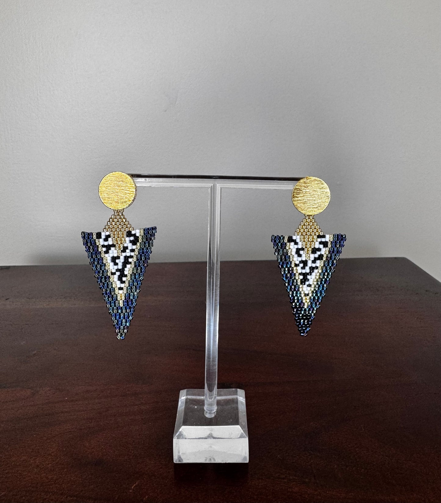 A pair of handcrafted Miyuki earrings with a long-triangle design, featuring gold-colored circles at the top and a pattern of black and white beads
