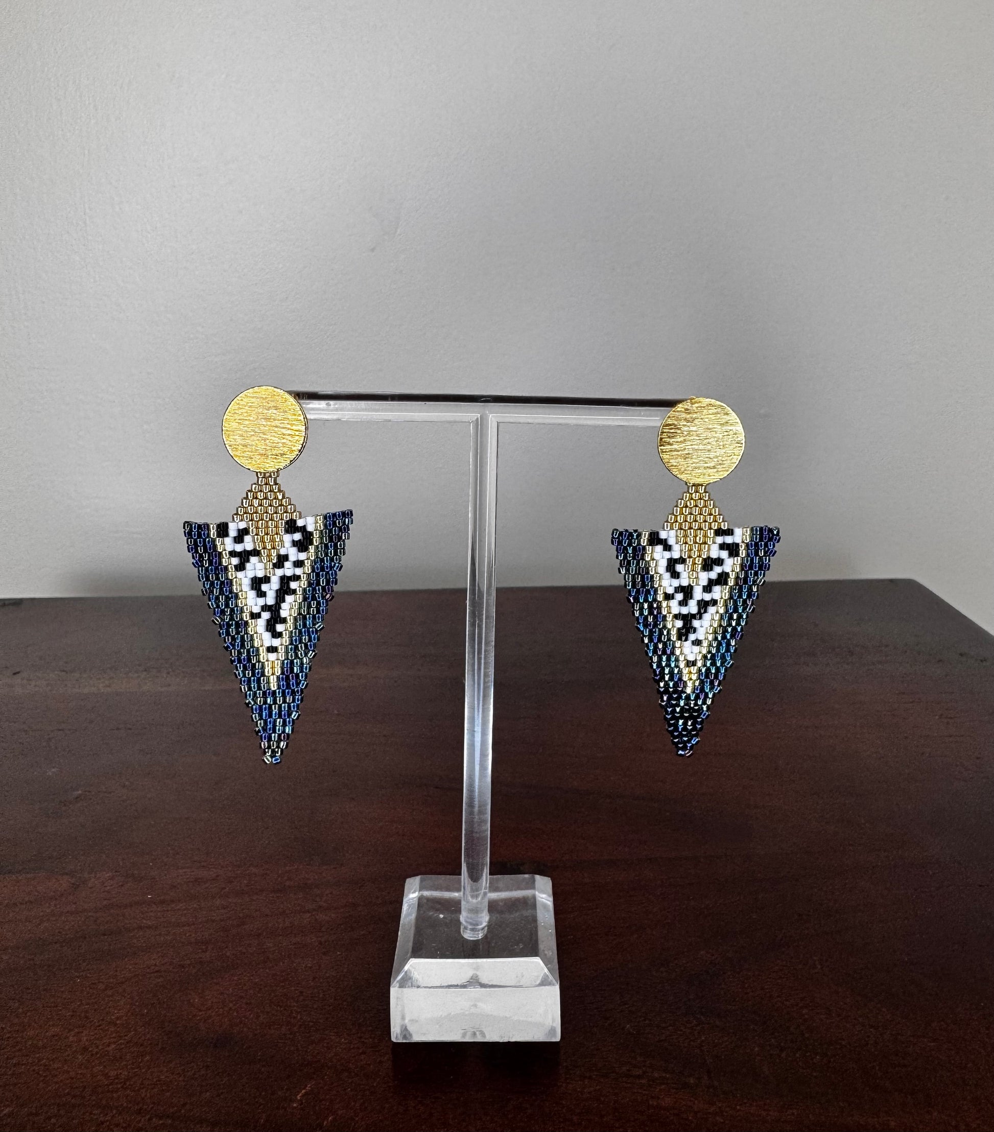 A pair of handcrafted Miyuki earrings with a long-triangle design, featuring gold-colored circles at the top and a pattern of black and white beads