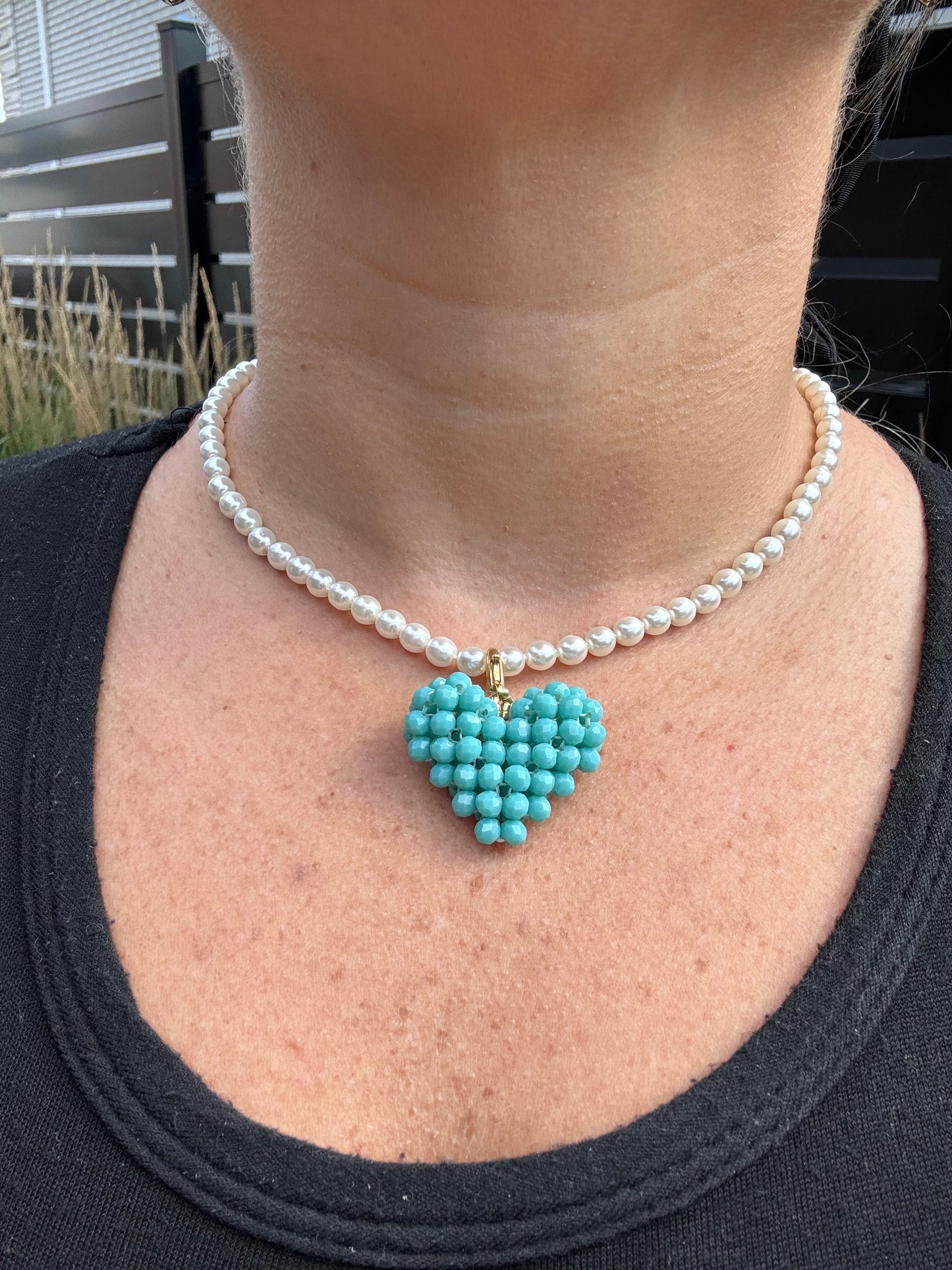 Close-up of a pearl bracelet and turquoise beaded heart charm 