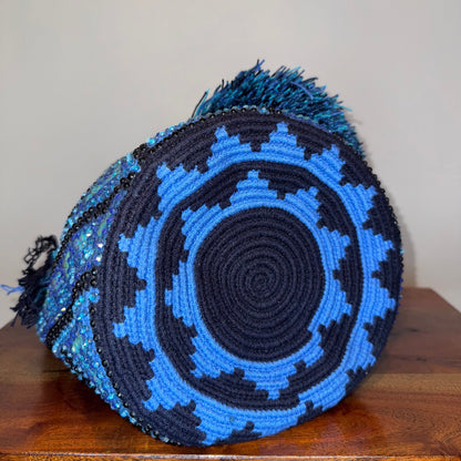 Blue and black woven basket on a wooden surface with a plain background